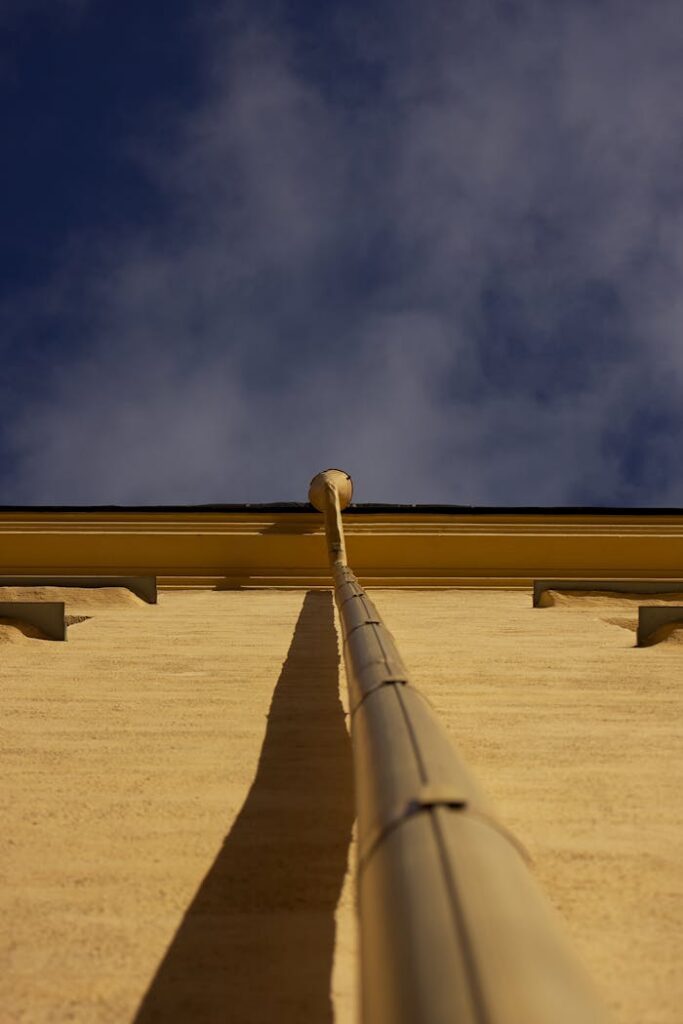 Dramatic low angle shot of a beige building facade with a cloudy sky overhead.
